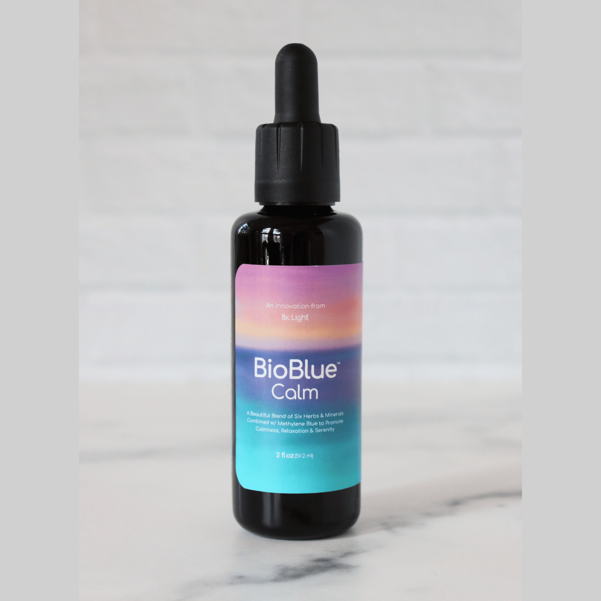 A bottle of BioBlue Calm supplement with a dropper, against a marble background.