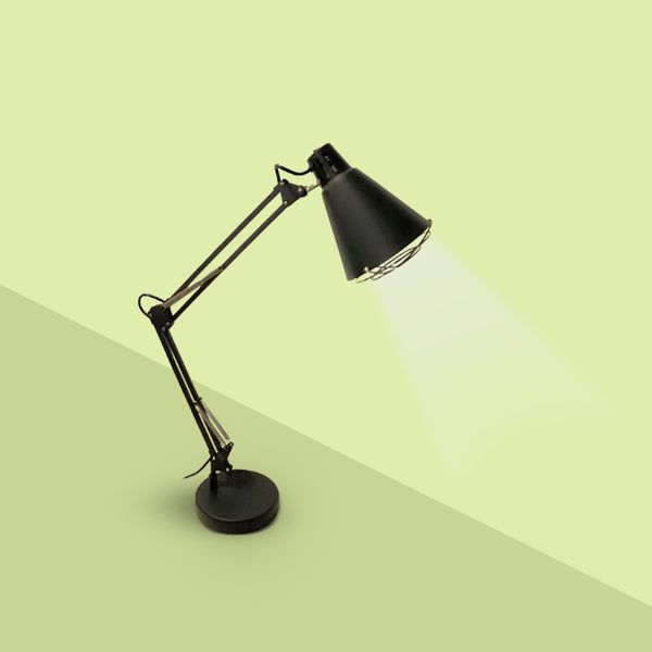 An elegant shielded desk lamp with a black finish, featuring a large lampshade and a circular base, illuminated with a bright light.